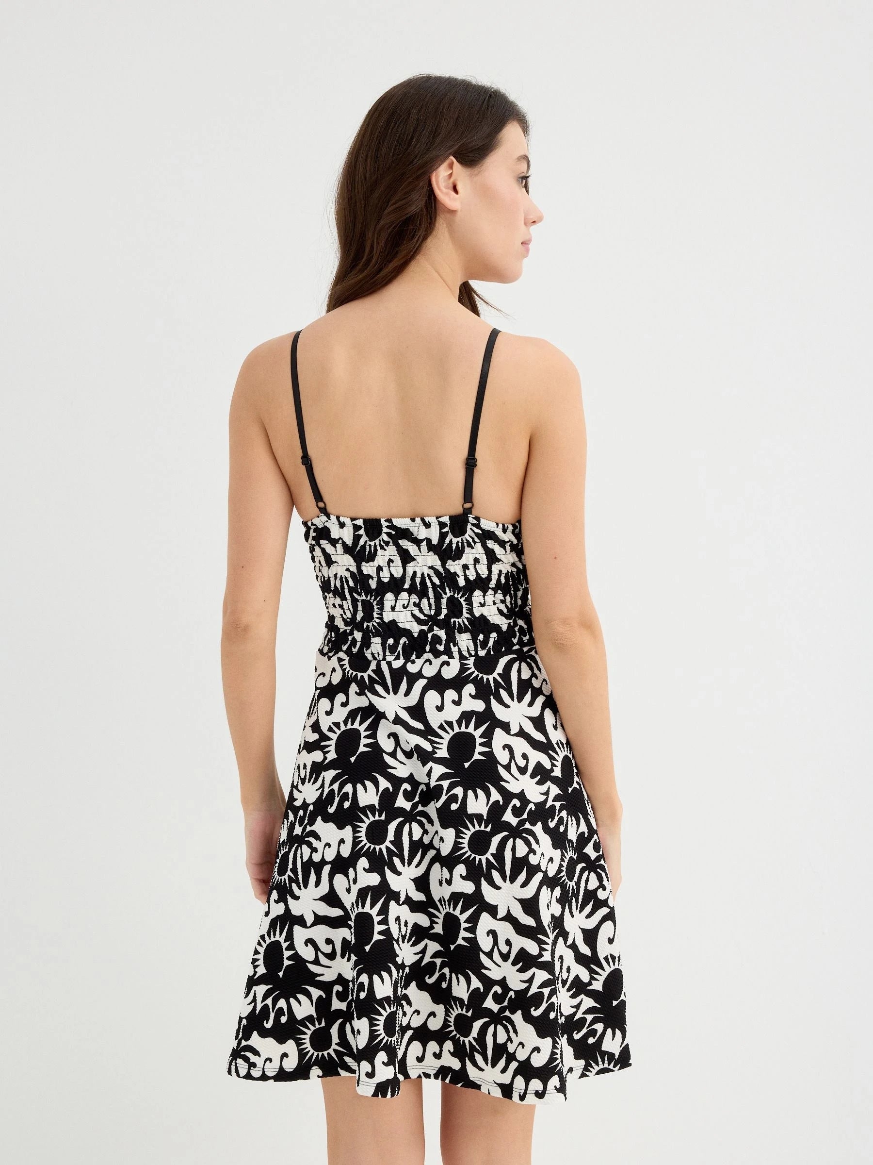 Tropical black and white short dress with adjustable straps, V-neck, and flattering cut for women, featuring a stylish design perfect for casual occasions and parties.